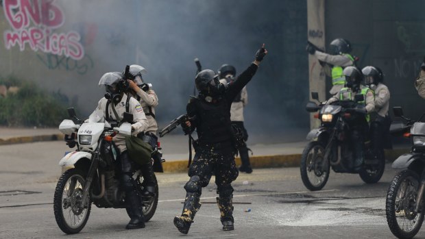 A police officer gives instruction to security forces advancing on demonstrators who were blocked from marching to the office of Attorney General Luisa Ortega Diaz.