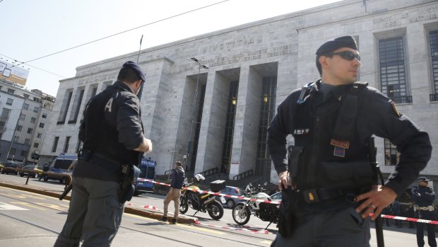 Police officers stand outside the tribunal building in Milan after the courtroom shooting.