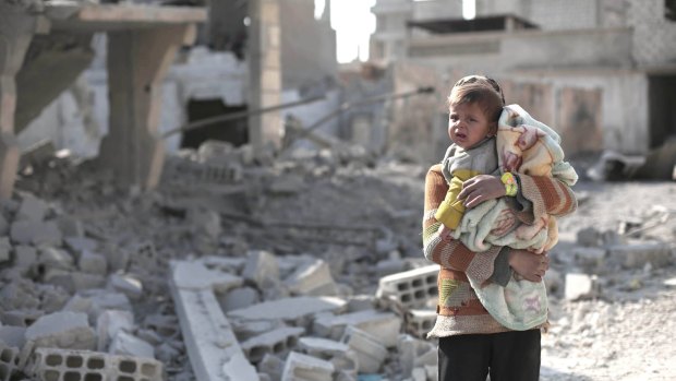A girl holds a baby in a destroyed neighbourhood in Eastern Ghouta, Syria.