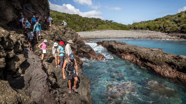 The group edges along rock ledges to the Herring rock pools.