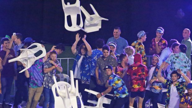 Spectators throw plastic chairs.