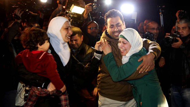 A man comforts the wife of captured Jordanian pilot Muath al-Kasaesbeh.
