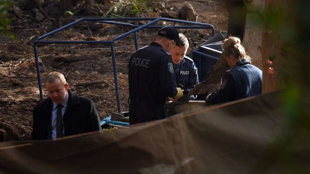 Police sift through soil at the crime scene.