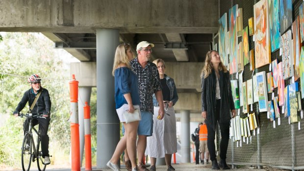 Artist Bruce Webb, centre, came with friends and relatives to view his and other artists' work at the the Art at Burnley Harbour exhibition under Citylink freeway at Burnley.