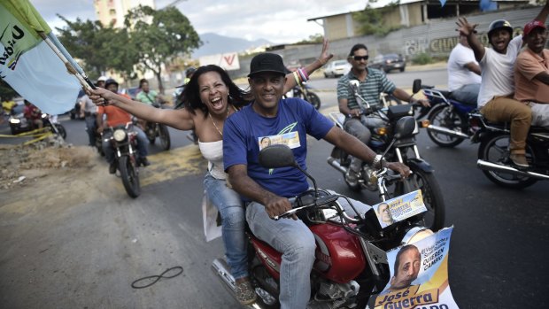 A caravan of anti-government bikers shout slogans as they drive past a polling centre in Caracas.
