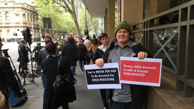 Brian Cherrie outside Melbourne Magistrates Court holding signs, ahead of Cardinal Pell's hearing.