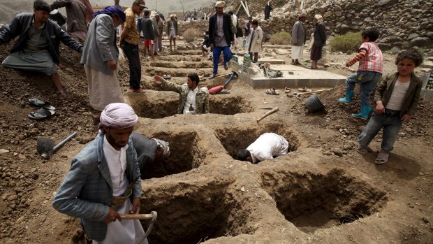People dig graves for the victims of an air strike in Okash village near Sanaa on April 4.