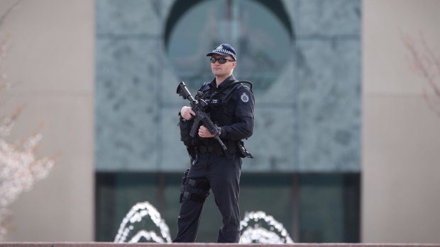 An AFP officer guards the perimeter of Parliament House.
