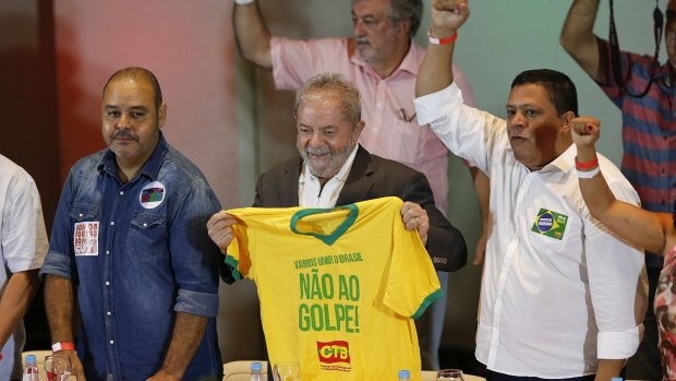 Former president Luiz Inacio Lula da Silva holds a shirt with text that reads "Let's unite Brazil, say no to a coup" during a meeting with union leaders in Sao Paulo on Wednesday.