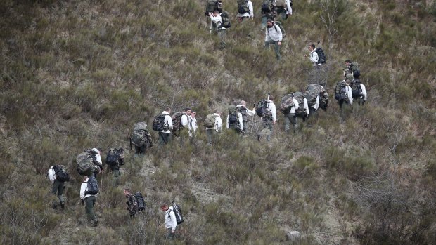 French military personel walk up the mountainside near the crash site.
