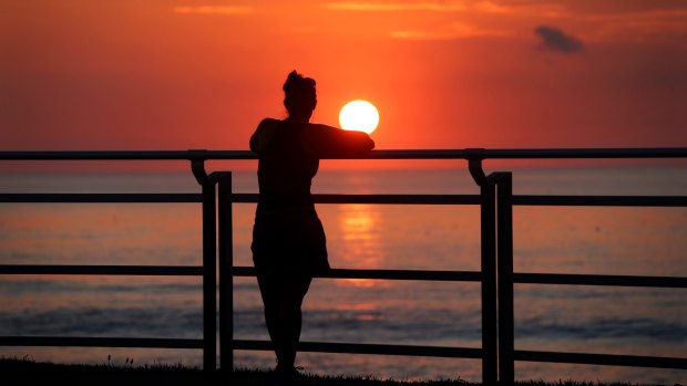 Wait for it: A walker on the Cronulla esplanade stops to enjoy the sunrise.