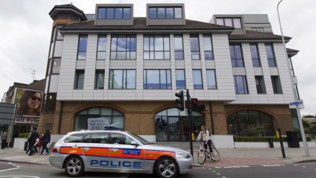 A police car drives on past the offices of notonthehighstreet.com in Richmond, where the body was found on the roof.