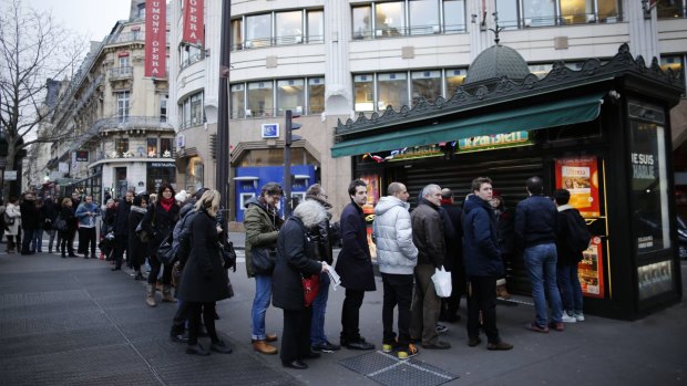People queue to get a copy of satirical French magazine <i>Charlie Hebdo</i>, titled "Tout est pardonne" ("All is forgiven") and showing a caricature of Prophet Mohammad, in front of a kiosk in Paris.