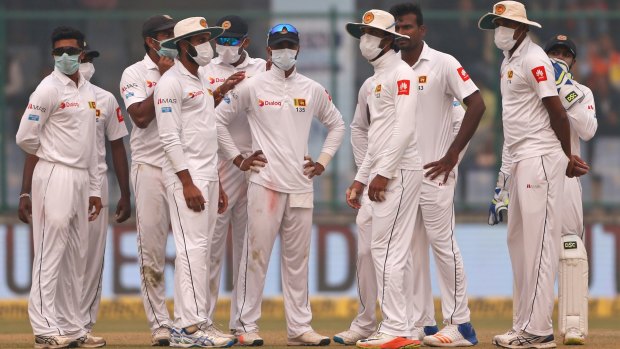Sri Lanka's players gather, wearing anti-pollution masks.