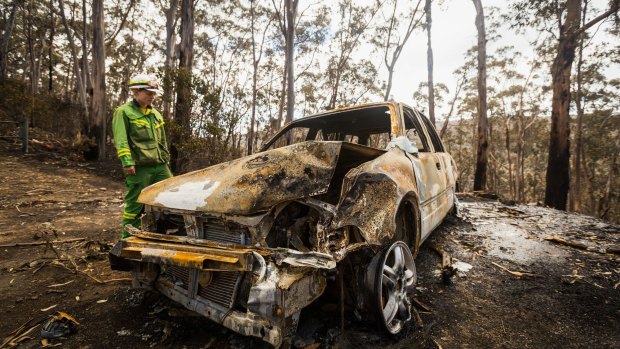 Firefighter Anna Cutriss inspects a burnt car in Wye River.