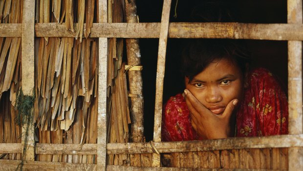 A Moken woman looks out from inside her home, Myanmar.