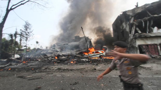 A police officer gestures at the crowd near the site where an Air Force cargo plane crashed in Medan.