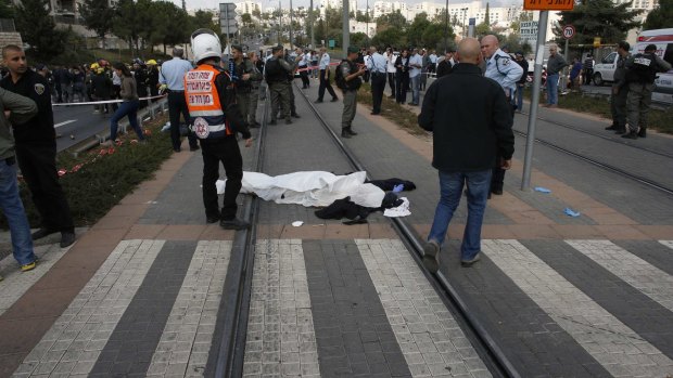 The covered body of a Palestinian motorist lies on the tracks of the light railway in Jerusalem following the attack.