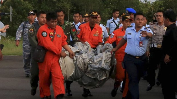 Rescue workers carry debris recovered from the ocean, presumed to be part of the AirAsia plane.