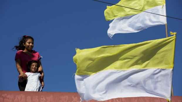Girls stand on the roof of a home next to Vatican-coloured flags as they wait for Pope Francis to leave the nearby Palmasola prison where he visited prisoners in Santa Cruz, Bolivia, on Friday.
