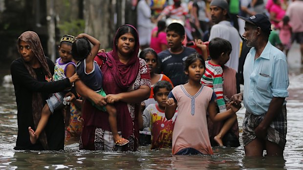 Sri Lankans wade through a road submerged in flood waters in Colombo.