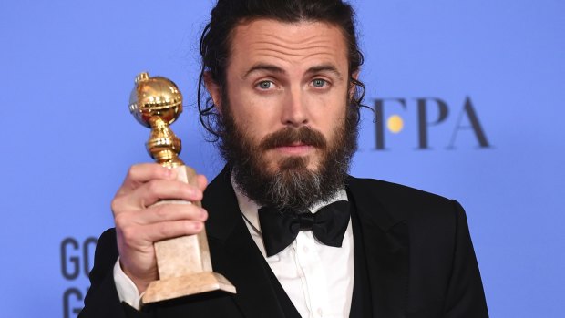 Casey Affleck poses in the press room with the Golden Globe award for his performance in <i>Manchester by the Sea</i>.