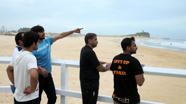 Friends of the missing swimmer watch a search at Nobbys Beach on Monday afternoon.