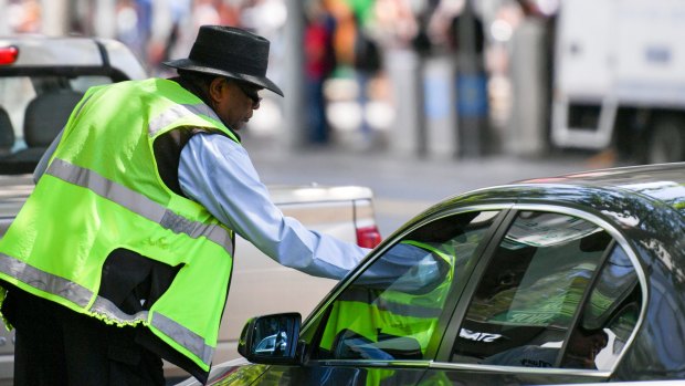 A parking inspector issues a ticket to a vehicle.