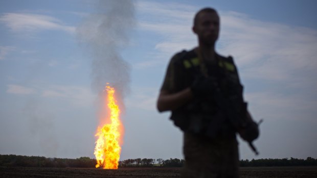 Ending Western sanctions without losing influence in eastern Ukraine is one of Putin's goals, according to Dr Igor Sutyagin. Pictured: a Ukrainian serviceman stands guard, as flames erupt in the distance from a damaged gas pipeline in the Donetsk region.
