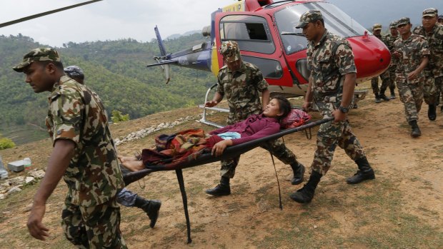 A woman suffering two broken legs from Saturday's massive earthquake, arrives by helicopter from the heavily-damaged Ranachour village.
