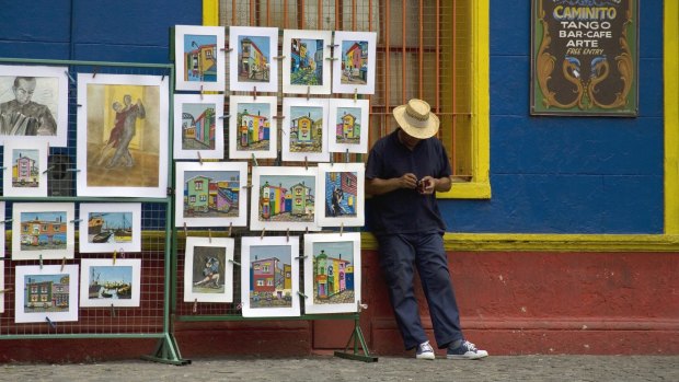 An artist stands alongside his work for sale, in the popular tourist area of La Boca.