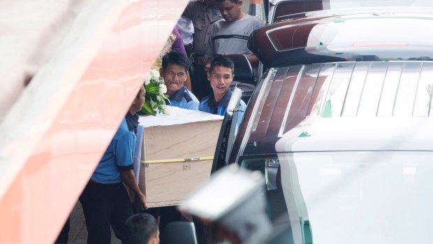 Workers at Abadi funeral home place one of the coffins into a hearse.