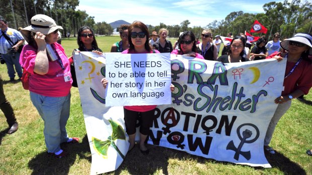 Yaping Wang holds a sign at a rally on the lawns of Parliament House to remember women who lost their lives to domestic violence this year.