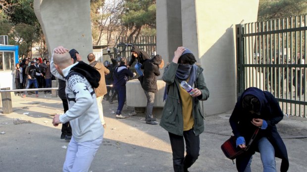 Students run away from stones thrown by police during a protest inside Tehran University.