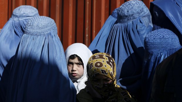 A girl looks on among Afghan women queueing for assistance donated by the United Nations High Commissioner for Refugees in Kabul.