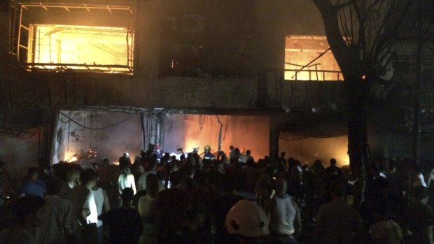 Iraqi firefighters and civilians gather at the site after a car bomb at a commercial area in Karada in Baghdad.