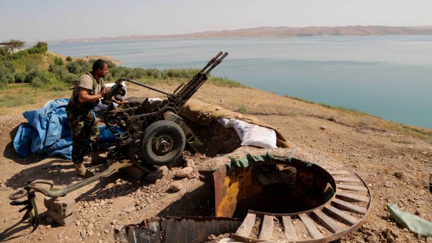 A Kurdish peshmerga fighter prepares his weapon at his combat position near the Mosul Dam.