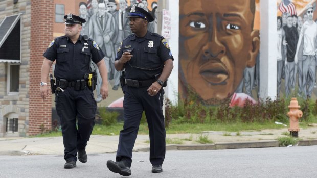 Baltimore police walk past a mural depicting Freddie Gray after prosecutors dropped remaining charges against the three officers  still awaiting trial.