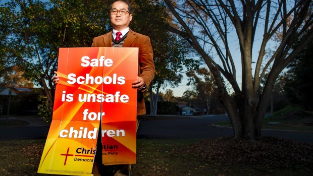 Rev. David Kim with one of the ACT Christian Democratic Party's anti safe schools campaign signs after it had been vandalised at his home. 