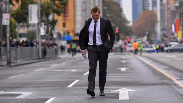 Collingwood coach Nathan Buckley is a solitary figure during the funeral procession.
