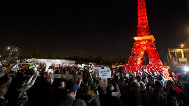 Activists gather next to a mini Eiffel Tower after a sit-in protest to denounce a draft text released at the climate conference.