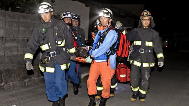 Firefighters carry an injured person after the earthquake, in the town of Mashiki.