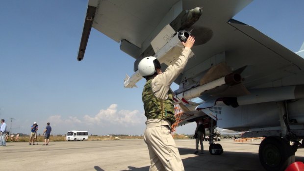 In this photo taken on Monday, a Russian pilot fixes an air-to-air missile at his Su-30 jet fighter before a take off at Hmeimim airbase in Syria. 