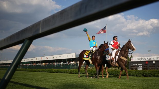 Jockey Victor Espinoza, left, raises his hat while riding American Pharoah after winning the 141st Kentucky Derby.