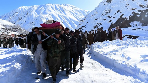 Afghan men carry a victim of the avalanches after funeral prayers.
