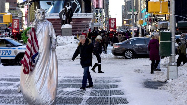 A costumed character, along with pedestrians, navigate sometimes slippery conditions in New York's Times Square Sunday in the wake of a storm that dumped heavy snow along the East Coast.