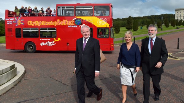 Tourists takes pictures from a sightseeing bus as Northern Ireland Deputy First Minister Martin McGuinness (left) and Sinn Fein president Gerry Adams (right) make their way to a press conference at Stormont House ahead of talks to save Northern Ireland's power-sharing government.