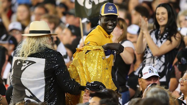 Magpies cheer squad leader Joffa Corfe tries to dress up the security guard with his famous "Game Over" golden jacket.