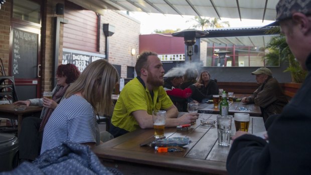 Jake Shumack (centre), smokes a cigarette in the courtyard of the Carlisle Hotel, Newtown.