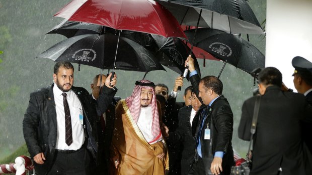 Saudi King Salman walks under the umbrellas during a heavy rain at the presidential palace in Indonesia.